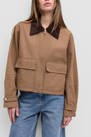 Detail front view of the Barn Jacket is a work-style zip-up jacket with a contrast corduroy collar, front flap pockets, and an adjustable button-back hem and sleeve cuffs for added utility.