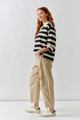 Woman wearing a black and white striped sweater with beige pants on a white background