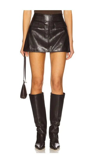 Person wearing a black leather mini skirt and knee-high boots on a white background