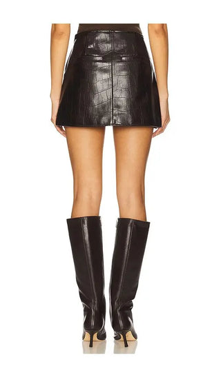 Person wearing a black leather skirt and knee-high boots on a white background