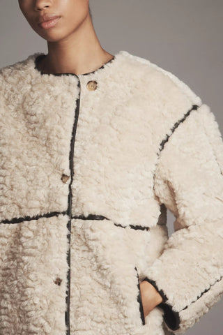 Close-up of a textured beige coat with black accents on a neutral background