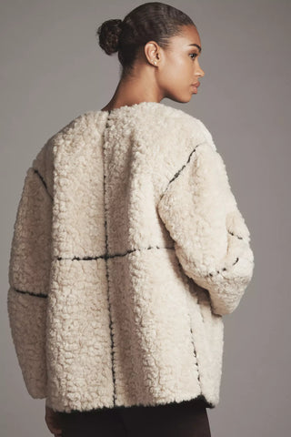 Woman wearing a textured beige coat against a gray background