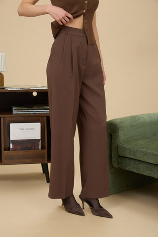 Person wearing brown high-waisted pants in a living room setting