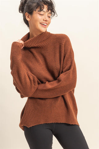 Woman wearing a brown sweater against a plain background