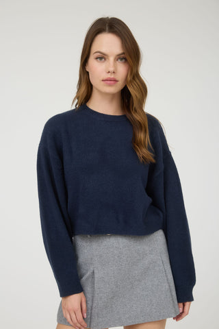 Woman wearing a navy sweater and gray skirt on a white background