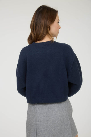 Woman wearing a navy sweater and gray skirt on a white background