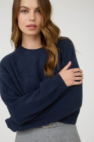 Woman wearing a navy sweater against a white background