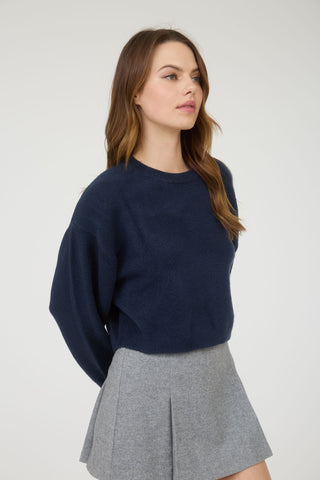 Woman wearing a navy sweater and gray skirt on a white background