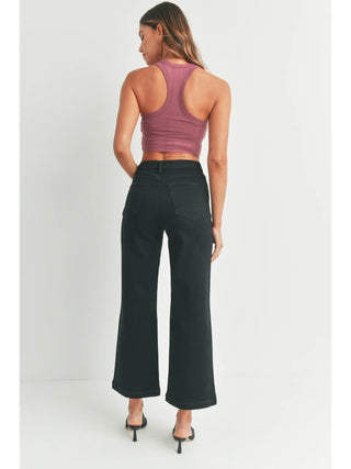 Woman wearing a purple tank top and black high-waisted pants on a white background