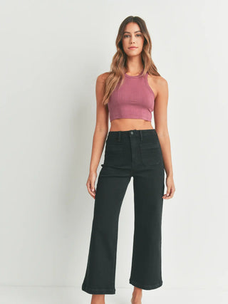 Woman wearing a pink crop top and black high-waisted pants on a white background