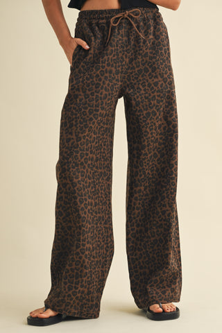 Leopard print pants worn by a person on a beige background
