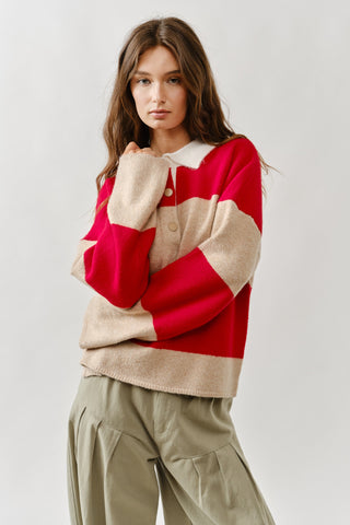 Woman wearing a red and beige sweater with a white collar on a plain background