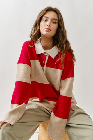 Woman wearing a red, beige, and white striped sweater against a plain background