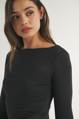 Woman wearing a black long-sleeve top against a white background