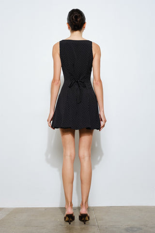 Woman wearing a black polka dot dress against a white background