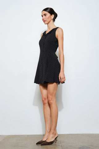 Woman wearing a black polka dot dress against a white background