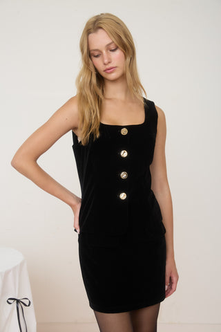 Woman wearing a black dress with gold buttons on a white background