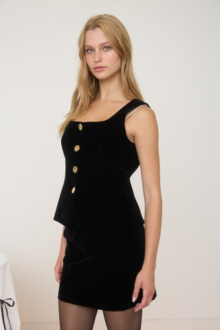 Woman wearing a black dress with gold buttons on a white background