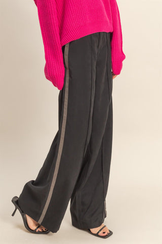 Person wearing a bright pink sweater and black pants on a beige background