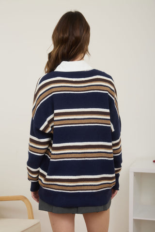 Person wearing a navy striped sweater with a white collar against a plain background