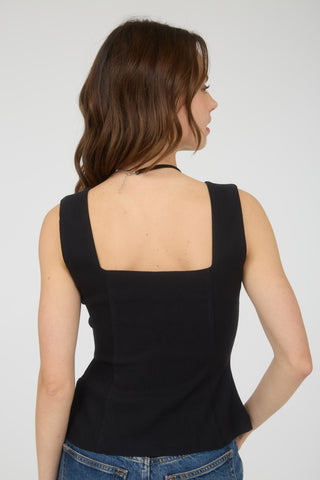 Woman wearing a black sleeveless top against a plain background