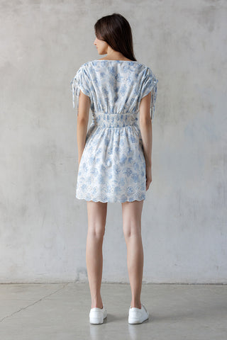 Woman wearing a light blue floral dress against a plain background