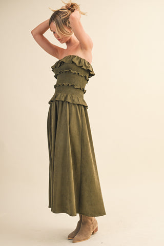 Woman wearing a green strapless dress with ruffled details on a beige background