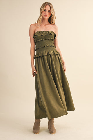 Woman wearing a green strapless dress with ruffled top on a beige background