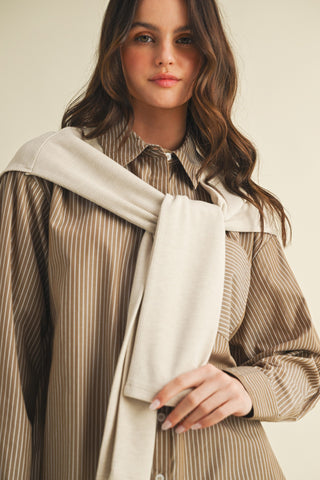 Woman wearing a striped shirt with a beige scarf against a neutral background
