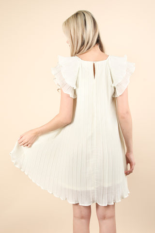 woman wearing pleated woven mini dress, back view showing off keyhole closure at neckline.