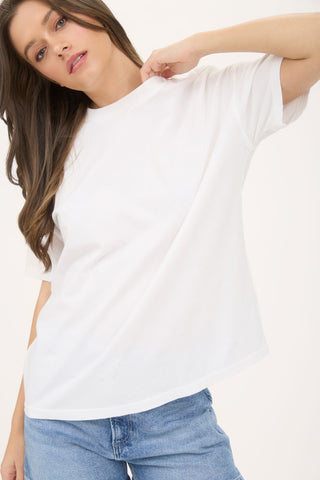 Woman wearing a white t-shirt and blue jeans against a plain background