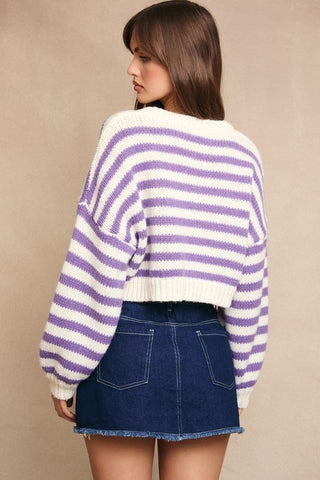 Woman wearing a purple and white striped sweater and blue denim skirt on a beige background