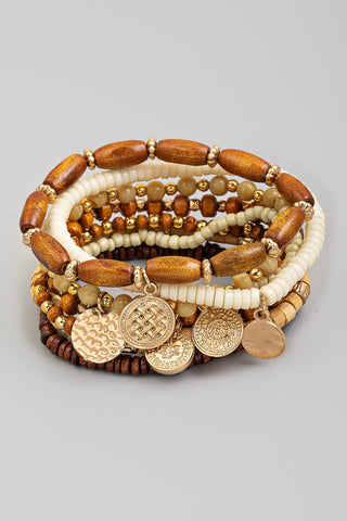 Stack of wooden and beaded bracelets with gold accents on a gray background