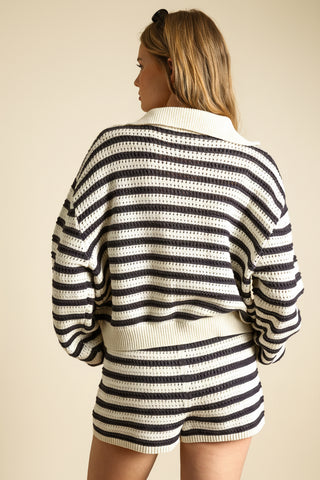 Person wearing a black and white striped outfit on a beige background