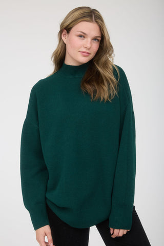 Woman wearing a dark green sweater against a white background