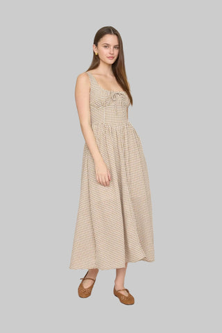 Woman in a beige checkered dress standing in a room with decorative elements.