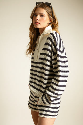 Woman wearing a black and white striped sweater against a beige background