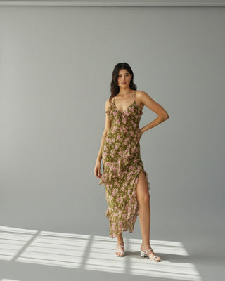 Woman in a floral dress standing outdoors with plants in the background