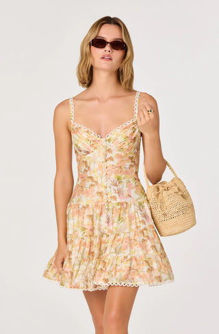 Woman wearing a floral dress holding a woven bag against a white background