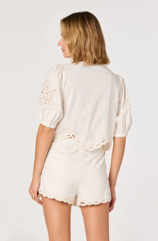 Woman wearing a cream-colored outfit with lace details on a white background