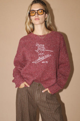 Person wearing a maroon sweater with a graphic design on a beige background