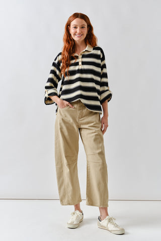 Woman wearing a black and white striped sweater with beige pants on a white background
