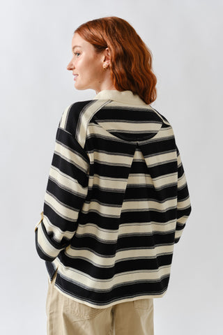 Person wearing a black and white striped sweater on a plain background