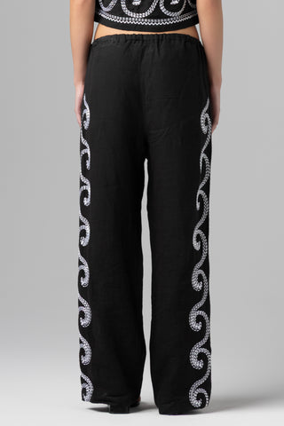 Black pants with white embroidery on a gray background
