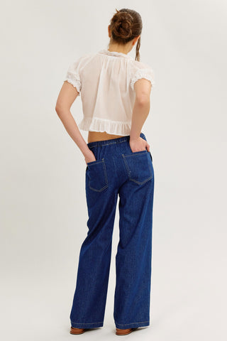 Model wearing blue denim drawstring pants, full outfit, showing off back pockets.