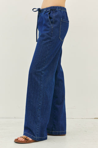 Blue denim drawstring pants showing off back pocket and length of pants.