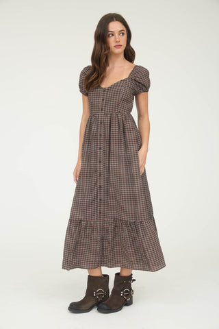 Woman wearing a brown checkered dress with puff sleeves on a white background