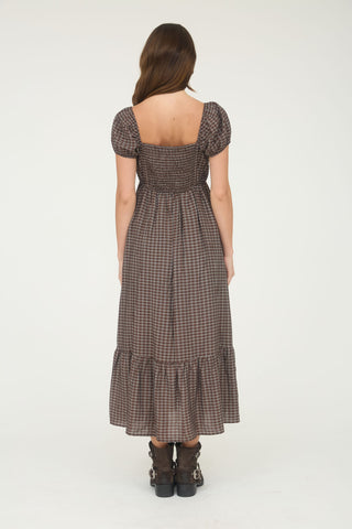 Woman wearing a brown checkered dress with short sleeves on a white background