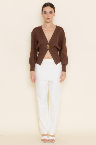 Woman wearing a brown top and white pants on a beige background