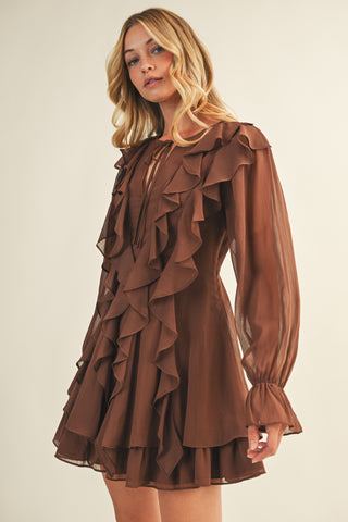 Woman wearing a brown ruffled dress against a plain background